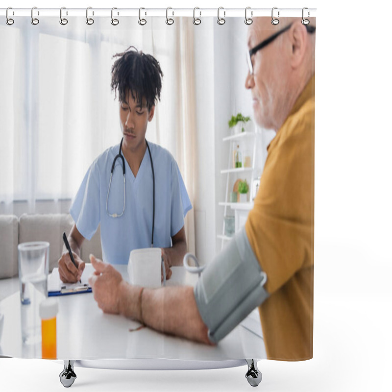 Personality  African American Nurse Writing On Clipboard Near Tonometer And Blurred Pensioner At Home  Shower Curtains