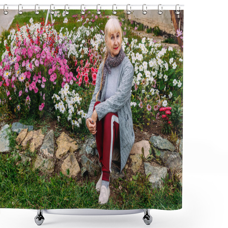 Personality  Fifty-year-old Attractive Blonde Woman In A Gray Cardigan Sitting Near A Flowering Flower Bed With Petunias In The Summer Shower Curtains