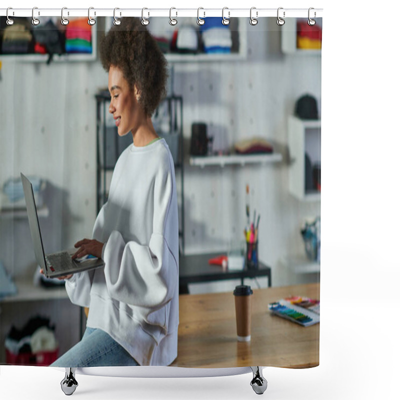 Personality  Positive Young African American Craftswoman In Jeans And Sweatshirt Using Laptop While Sitting Near Coffee To Go On Table In Print Studio, Enthusiastic Business Owner Working In Workshop Shower Curtains