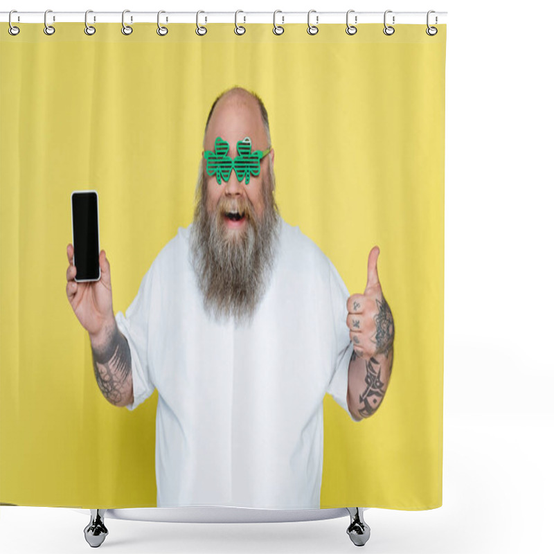 Personality  Joyful Overweight Man In Clover-shaped Glasses Showing Thumb Up While Holding Smartphone Isolated On Yellow Shower Curtains