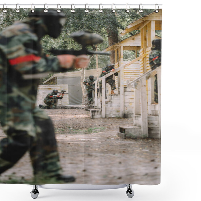 Personality  Selective Focus Of Paintballer In Camouflage And Protective Mask Aiming By Marker Gun While His Team Standing Behind Outdoors  Shower Curtains