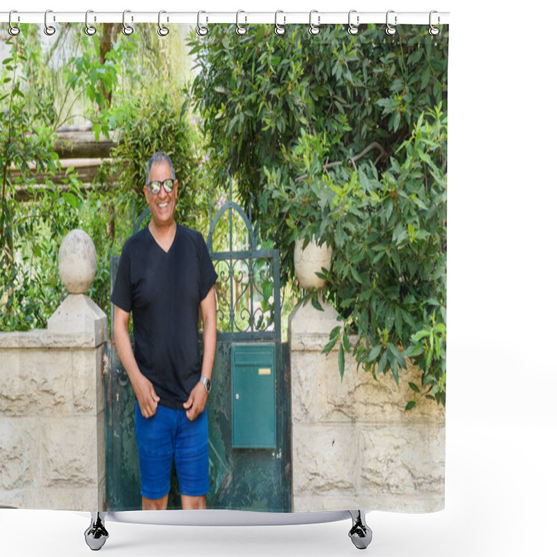 Personality  Joyful Senior Man In Casual Black T-shirt And Blue Shorts Stands By Rustic Green Gate, Surrounded By Lush Greenery In Tranquil Garden Setting.Perfect For Themes Of Travel, Tourism, And Outdoor Leisure Shower Curtains