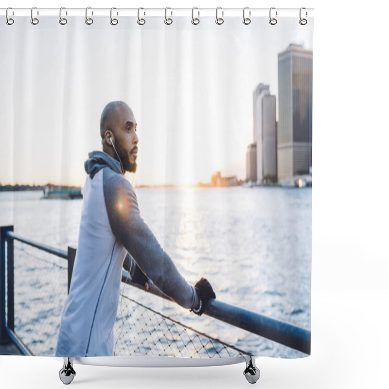 Personality  Side View Of Mindful Fit Ethnic Male In Earphones And Sport Clothes Standing Near River On Embankment Looking Away Pensively Shower Curtains