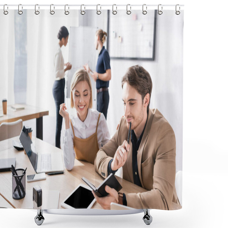 Personality  Happy Office Workers Looking At Notebook While Sitting At Table In Office With Blurred Multicultural Colleagues Working On Background Shower Curtains