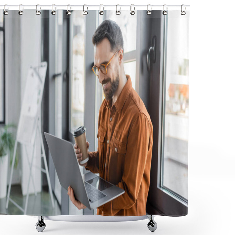 Personality  Brunette And Bearded Businessman In Eyeglasses And Stylish Shirt Holding Disposable Cup With Coffee And Looking At Laptop Near Flip Chart On Blurred Background In Office Shower Curtains