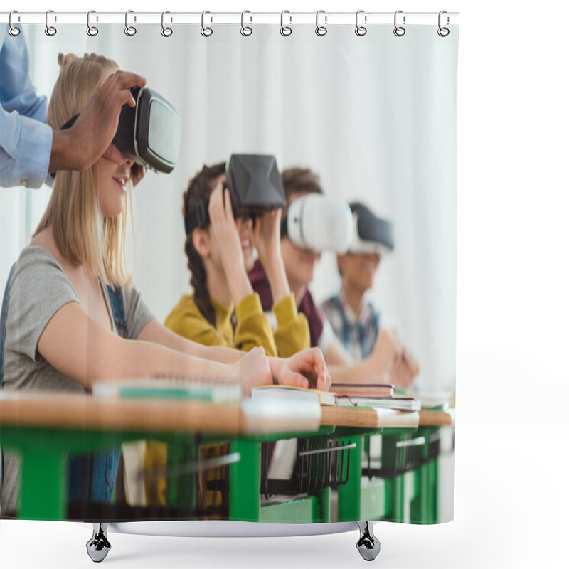 Personality  Cropped Image Of African American Teacher Adjusting Virtual Reality Headset To Teenage Schoolgirl With Classmates Sitting Behind Shower Curtains