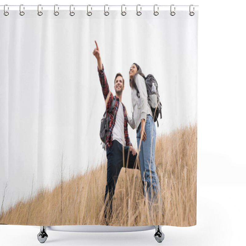 Personality  Low Angle View Of Smiling Man With Backpack Pointing With Finger Away Near African American Woman While Standing On Grassy Hill With Sky At Background  Shower Curtains