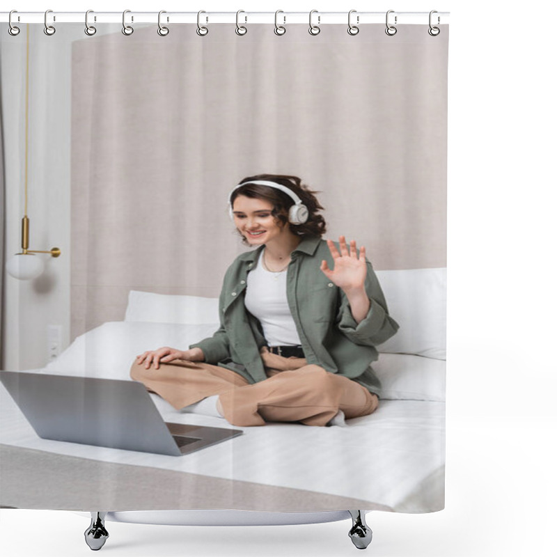 Personality  Overjoyed Woman With Wavy Brunette Hair, In Wireless Headphones And Casual Clothes Sitting On Bed And Waving Hand During Video Call On Laptop Near White Pillows And Wall Sconce In Hotel Room Shower Curtains