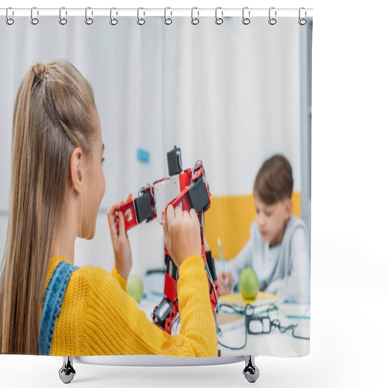 Personality  Schoolgirl Sitting At Table And Holding Robot Model During STEM Lesson With Classmate On Background Shower Curtains