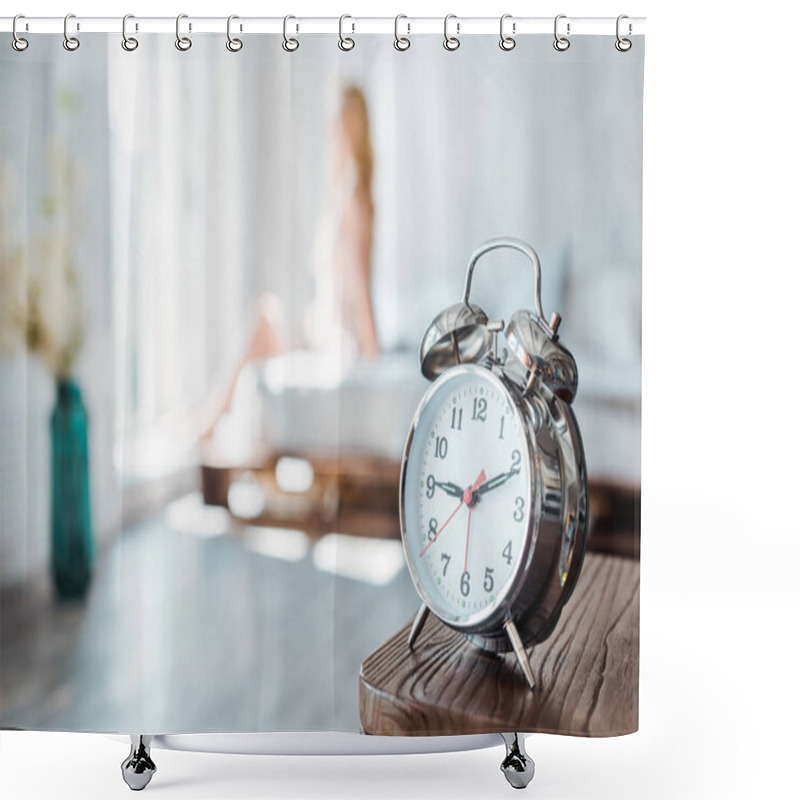 Personality  Close-up View Of Alarm Clock On Wooden Table And Young Woman Sitting On Bed Behind Shower Curtains