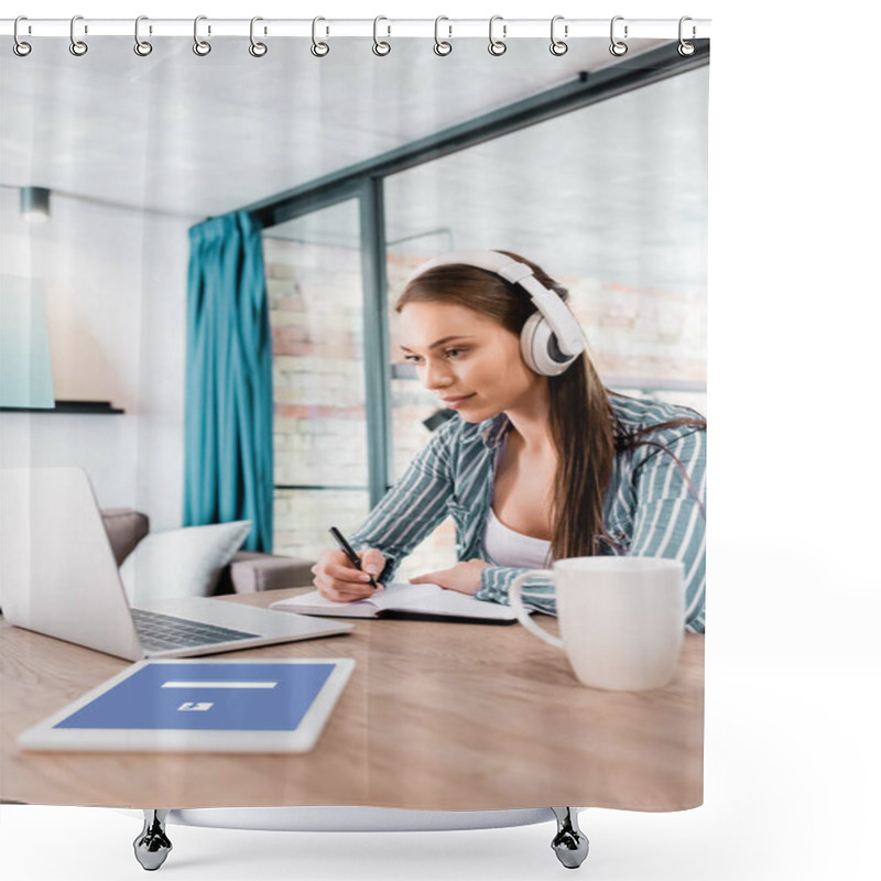 Personality  KYIV, UKRAINE - APRIL 29, 2020: Selective Focus Of Girl In Wireless Headphones Writing In Notebook Near Laptop And Digital Tablet With Facebook App, Online Study Concept Shower Curtains